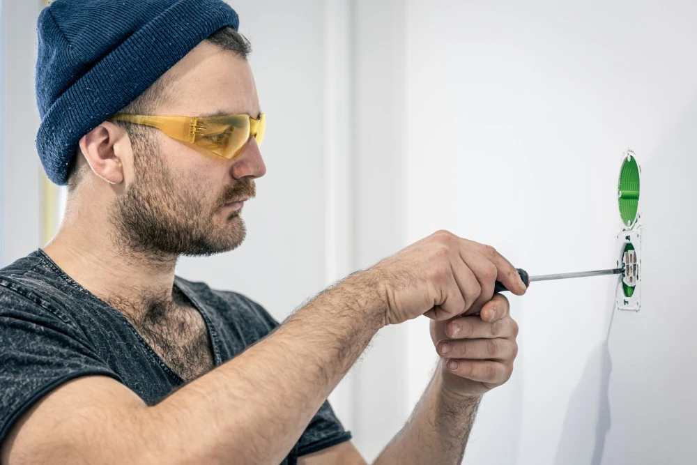 Electrician is mounting electric sockets white wall indoors