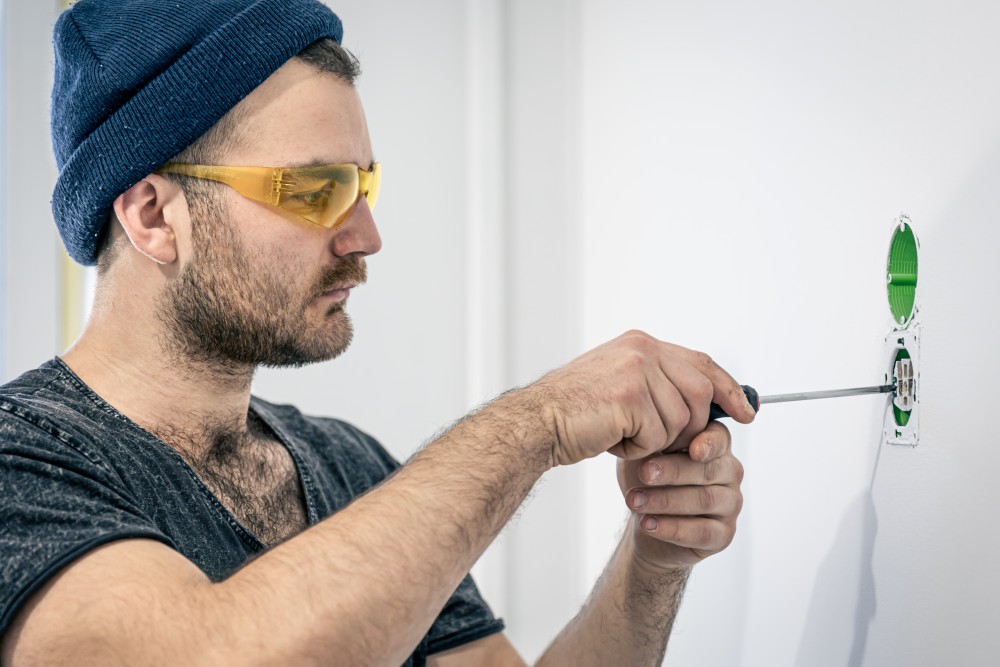 Electrician is mounting electric sockets white wall indoors