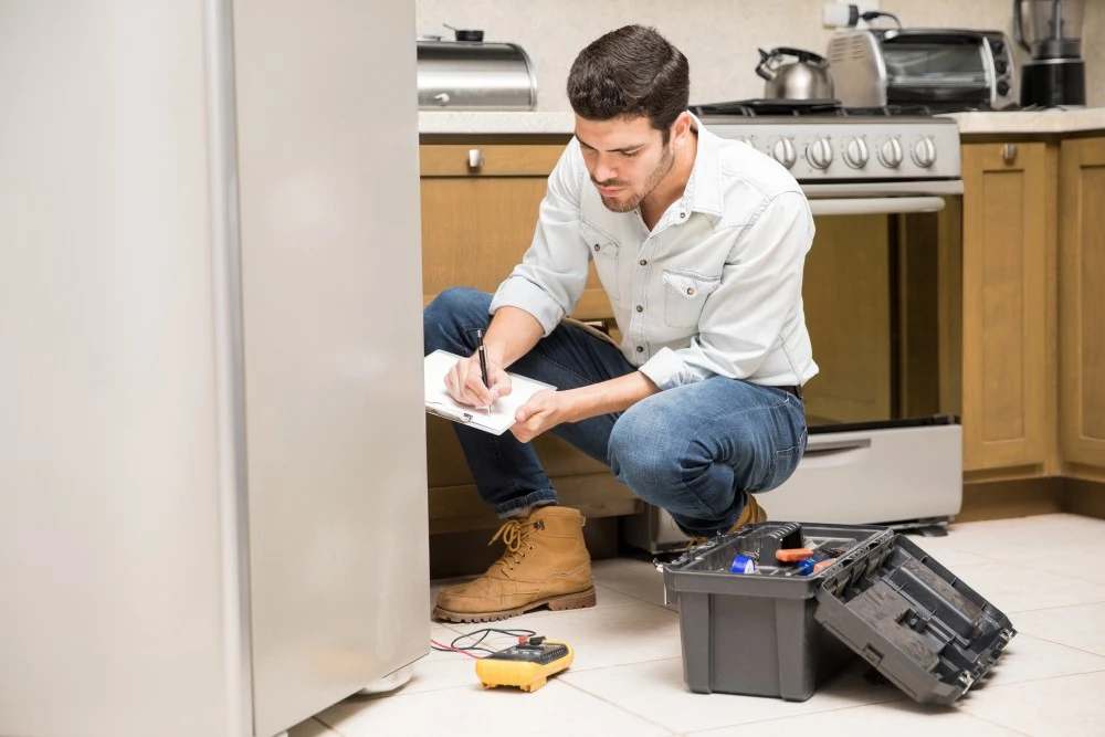 Portrait handsome male technician doing work report broken fridge home kitchen